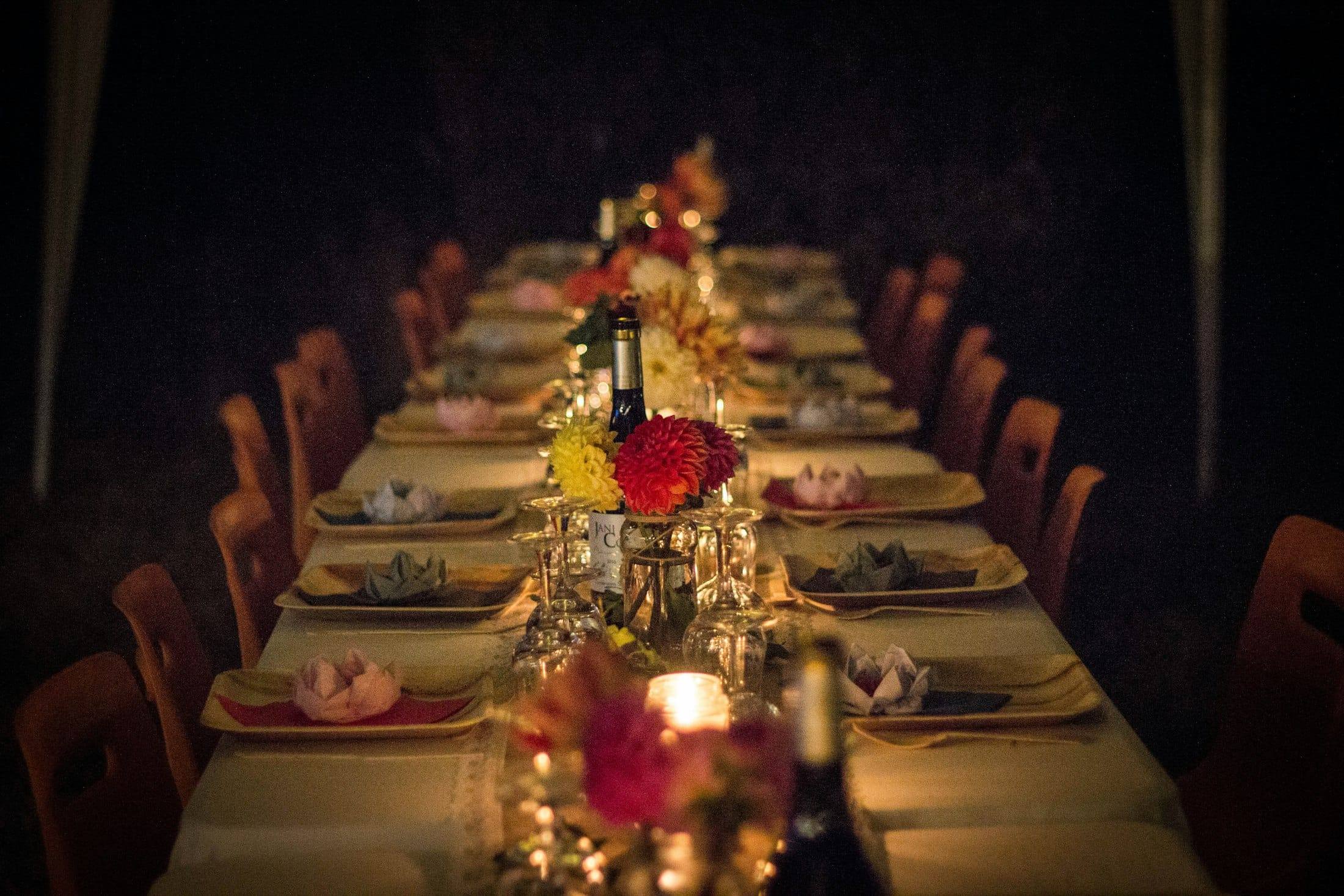 Long dinner table set with candles and flowers at night