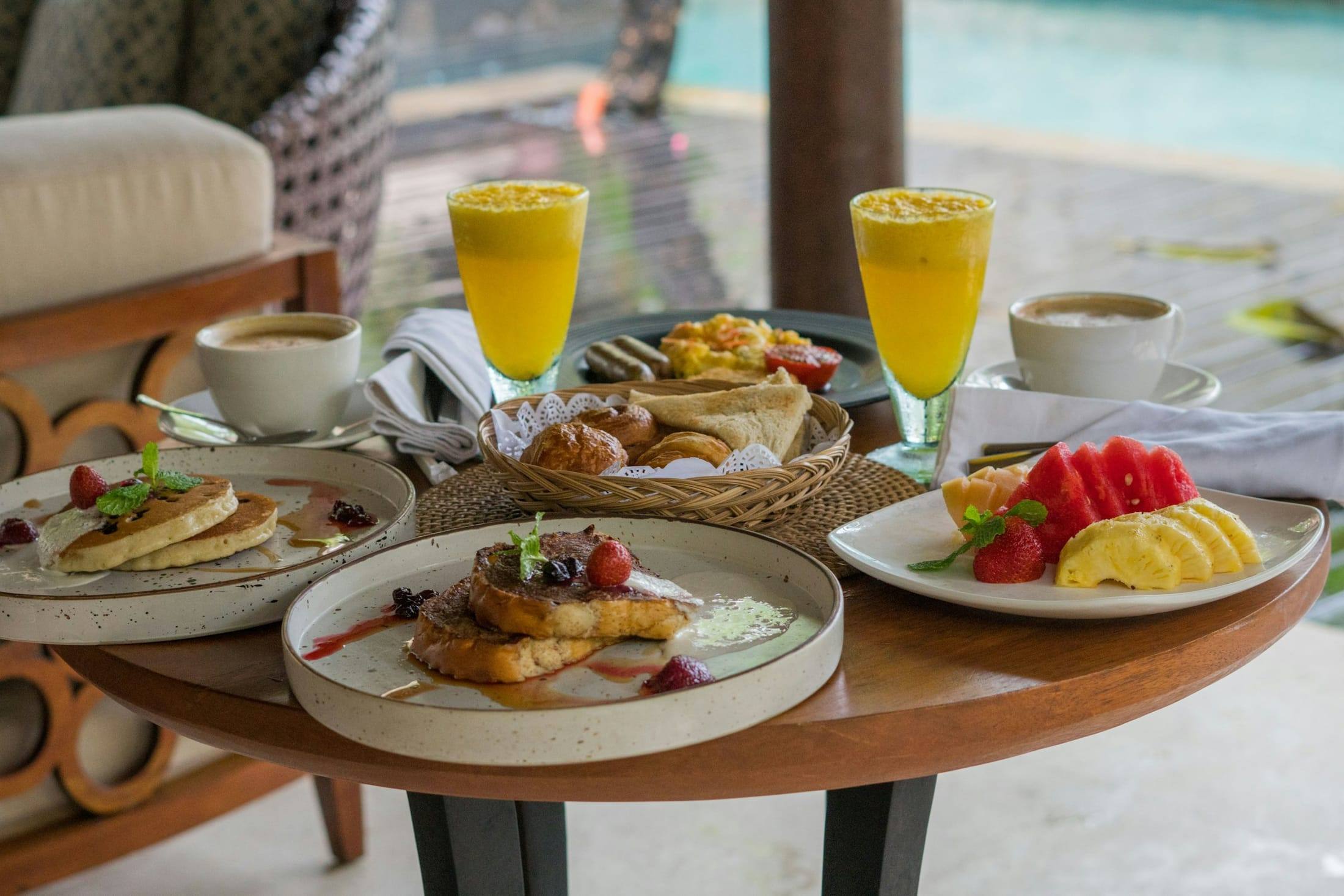 Breakfast spread with juice, coffee and fruit beside a pool
