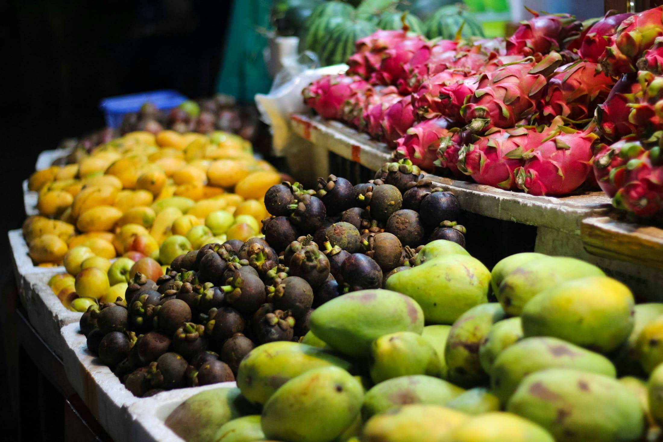 Market stall piled with mangoes, dragon fruit and tropical produce